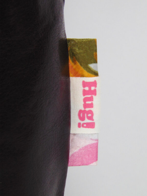 Close up picture of the label stitched into the right side seam of each shopper. Each bag has its own label made from fabric scraps. This label has flowers in pink, yellow and green.