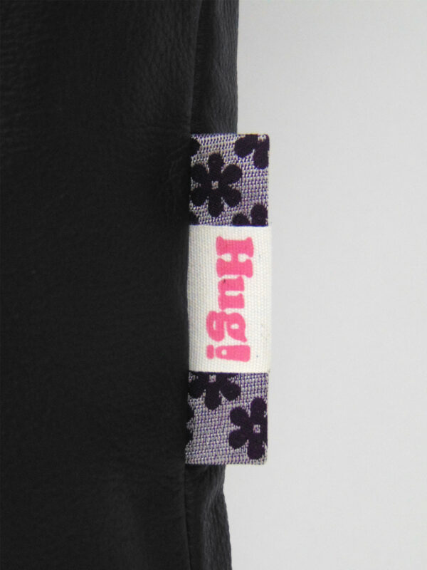Close up picture of the label stitched into the right side seam of each shopper. Each bag has its own label made from fabric scraps. This label is purple with flowers.